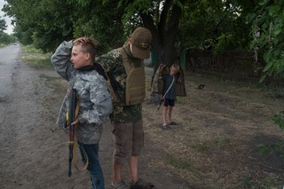 Junge Burschen spielen "Checkpoint". Sie versuchen, Autos zu stoppen und imitieren dabei das Verhalten ukrainischer Soldaten. Gebiet Donezk, 09.07.2022 | Young boys play ‘checkpoint’. They try to stop cars, imitating the behaviour of Ukrainian soldiers. Donetsk region, 09.07.2022